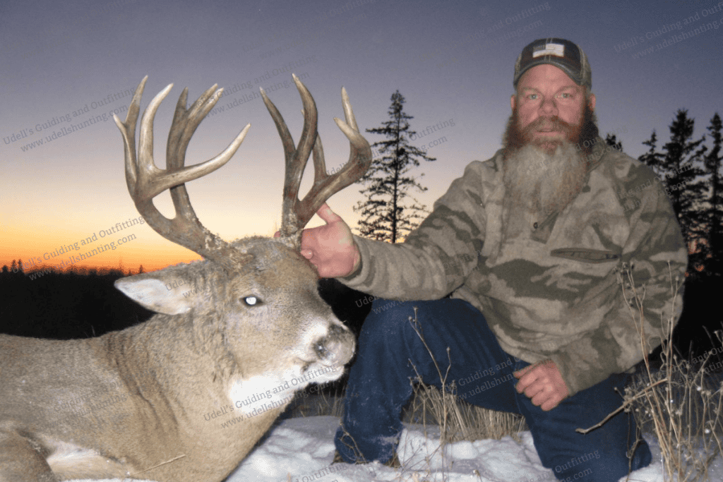 A man with a beard and camouflage hat is posing with a deer.