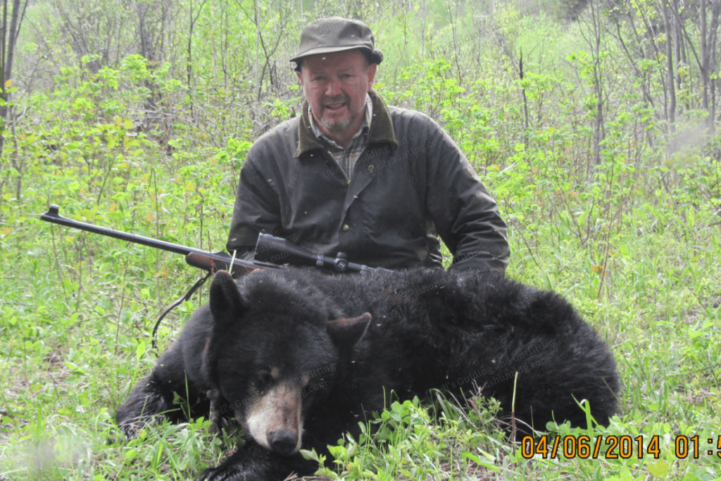 A man with a rifle and a black bear.