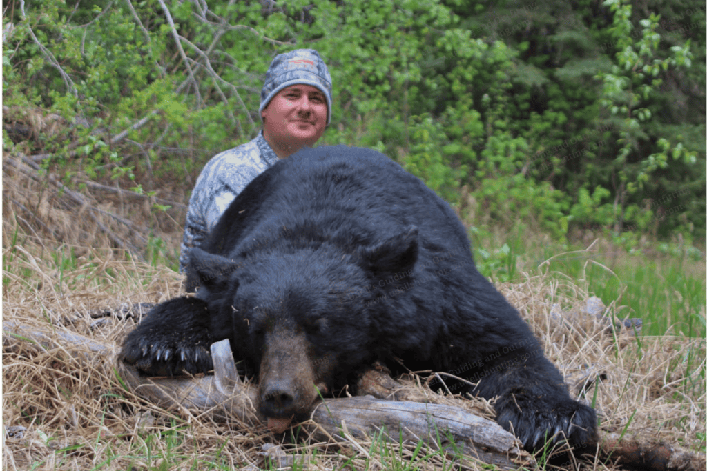 A man is posing with a black bear.