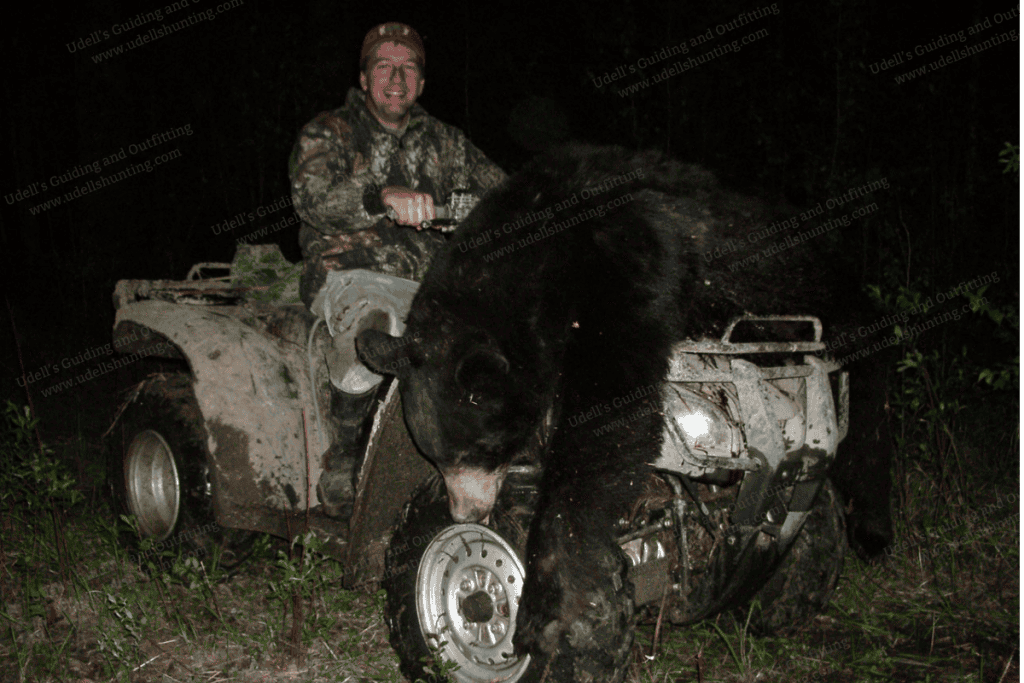 A man riding a quad bike with a bear on it.
