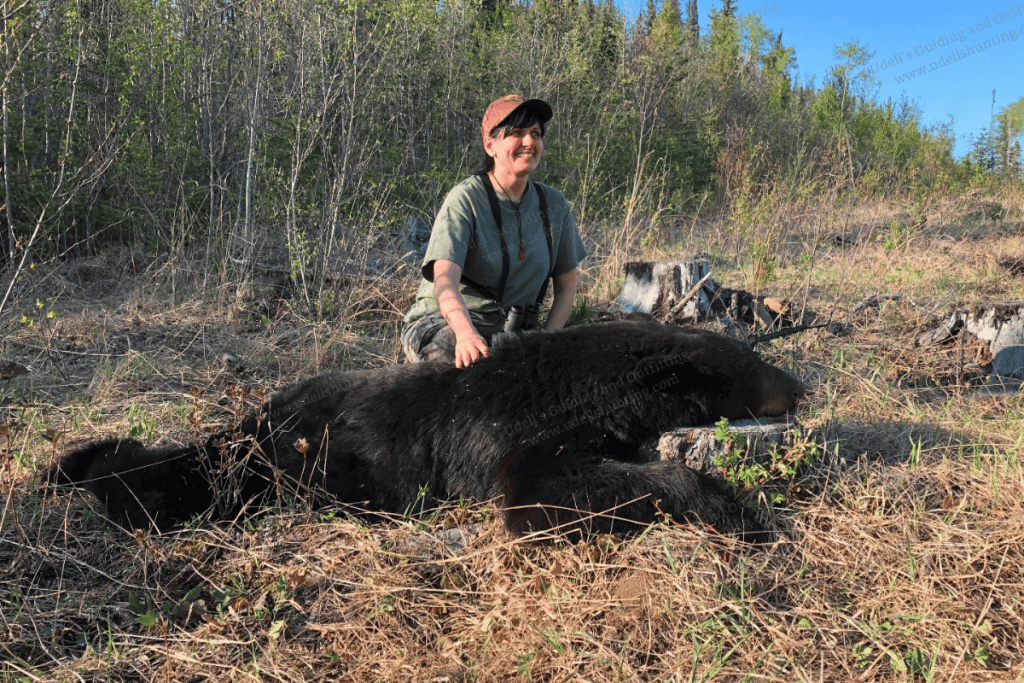 A woman kneeling down next to a black bear.