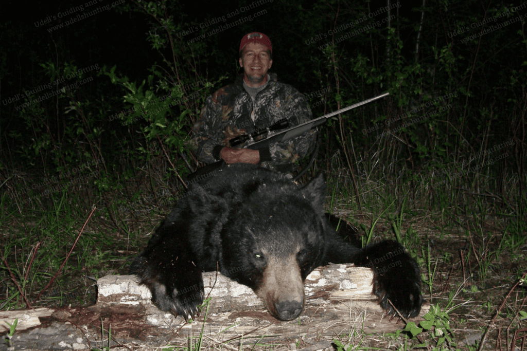A man with a rifle and a black bear.